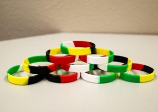 Ten multi-colored wristbands, showing the colors of the "Wordless Book", placed in a pyramid pose on a white table.